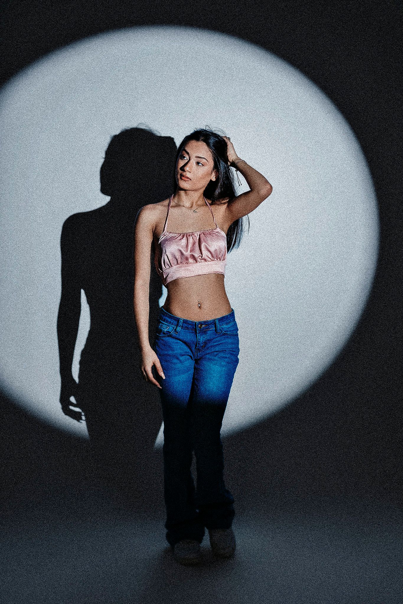 Dramatic lighting creates dynamic shadows in this artistic fashion photoshoot with denim and pink top.