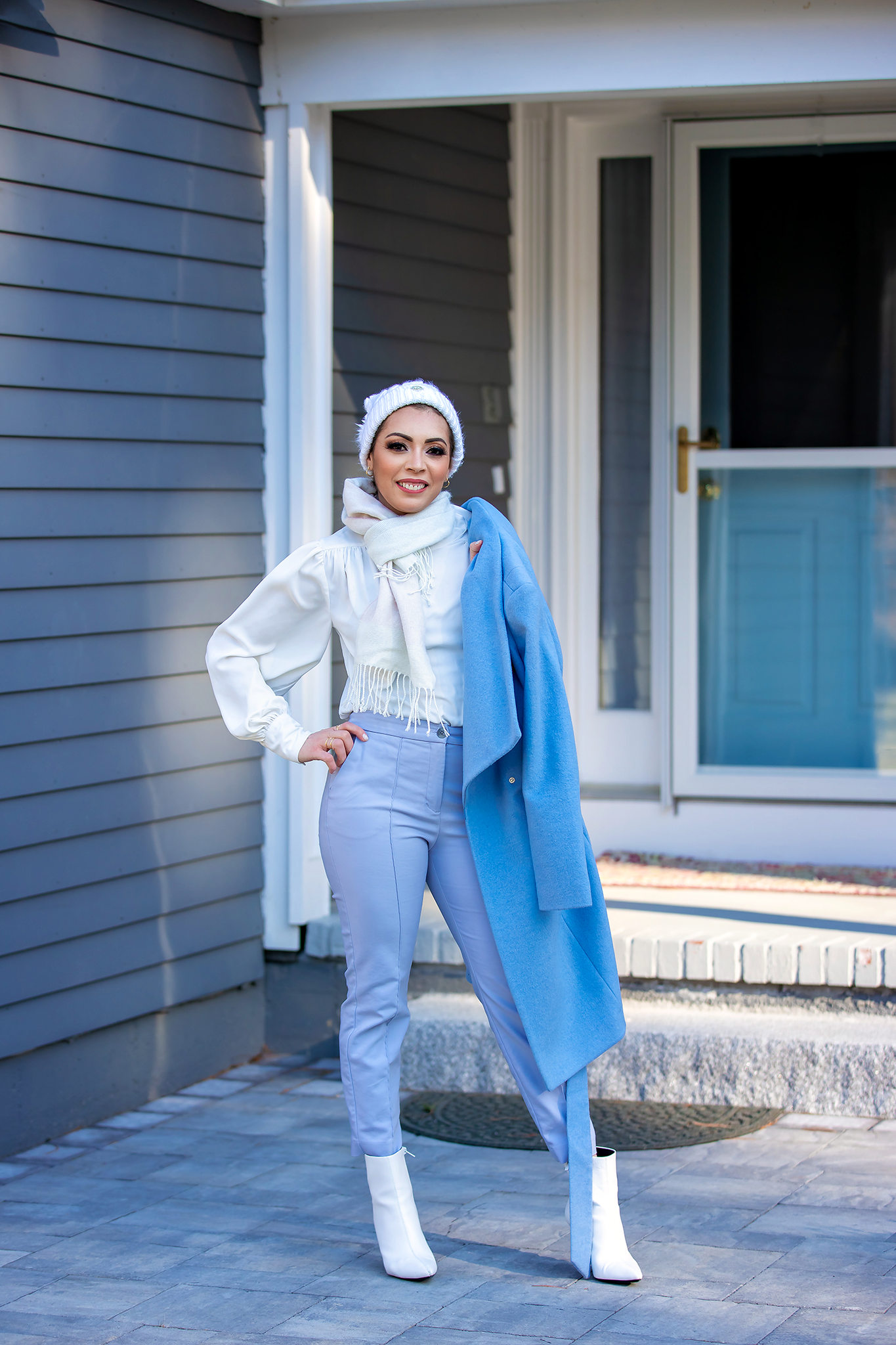 Stylish white and blue outfit ensemble photographed against modern house exterior.