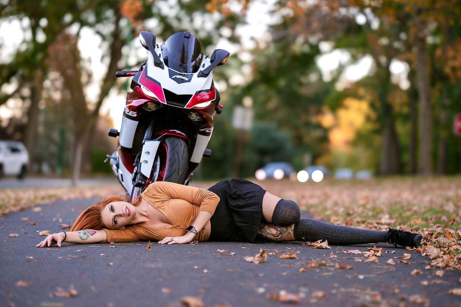 Sport motorcycle parked on leaf-covered ground in fall setting.