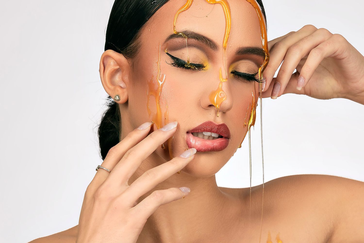 Close up beauty shot with honey dripping effect and dramatic makeup styling.