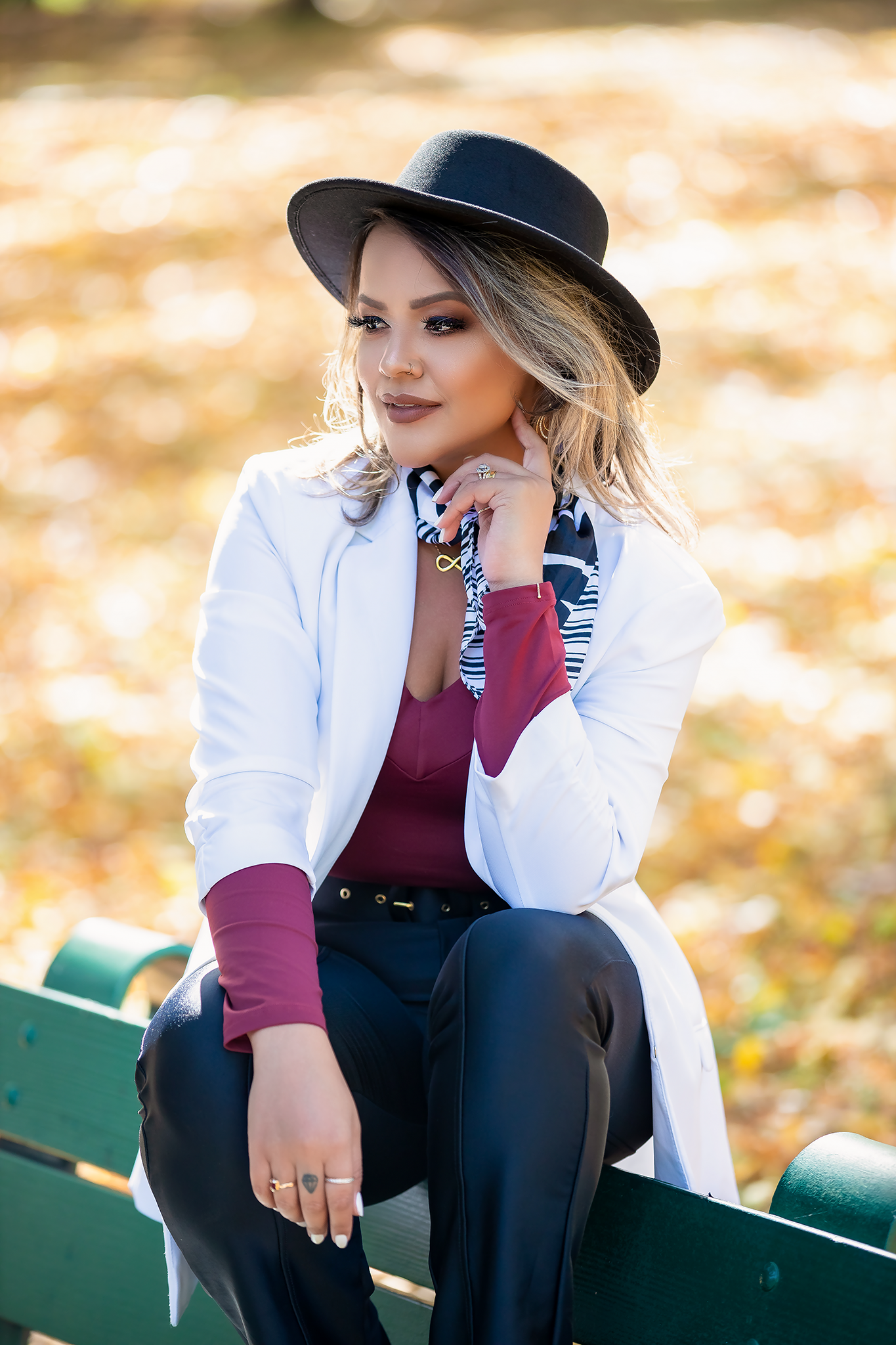 Outdoor portrait session featuring white blazer and hat against autumn background.