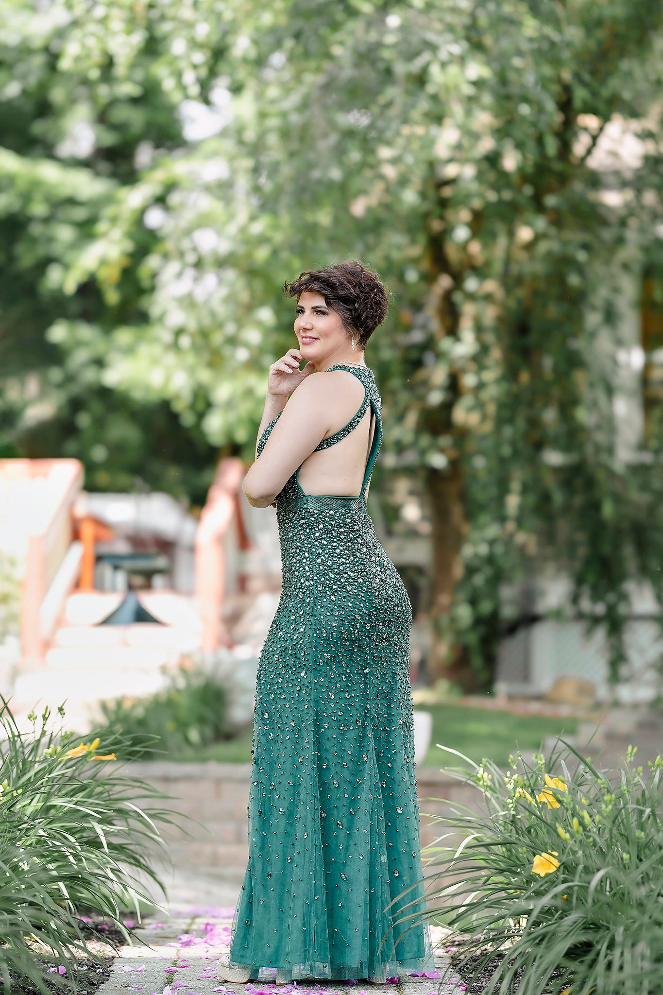 Garden photoshoot featuring emerald green dress among blooming flowers.