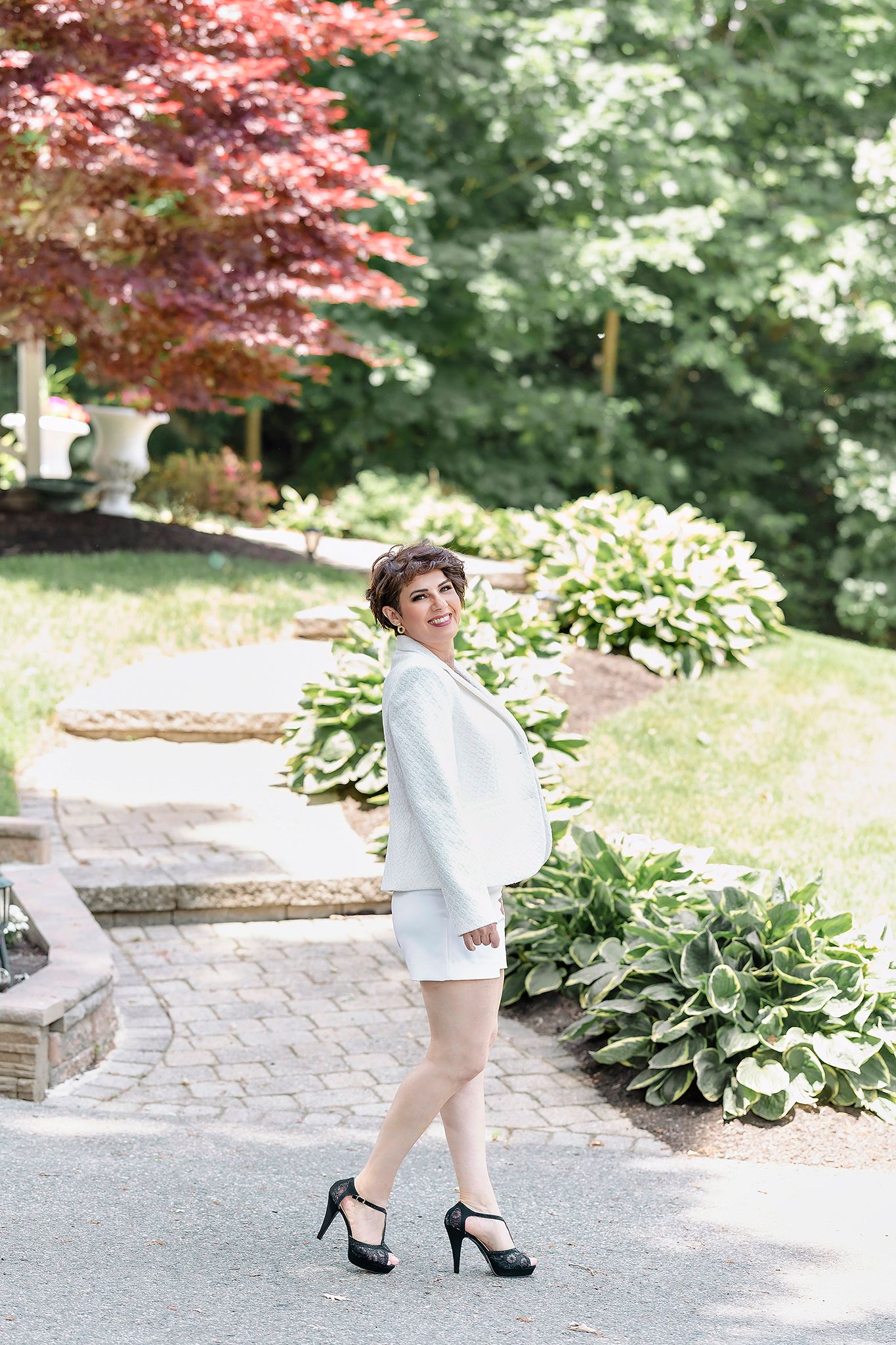 Elegant outdoor photos in white outfit walking on stone pathway.
