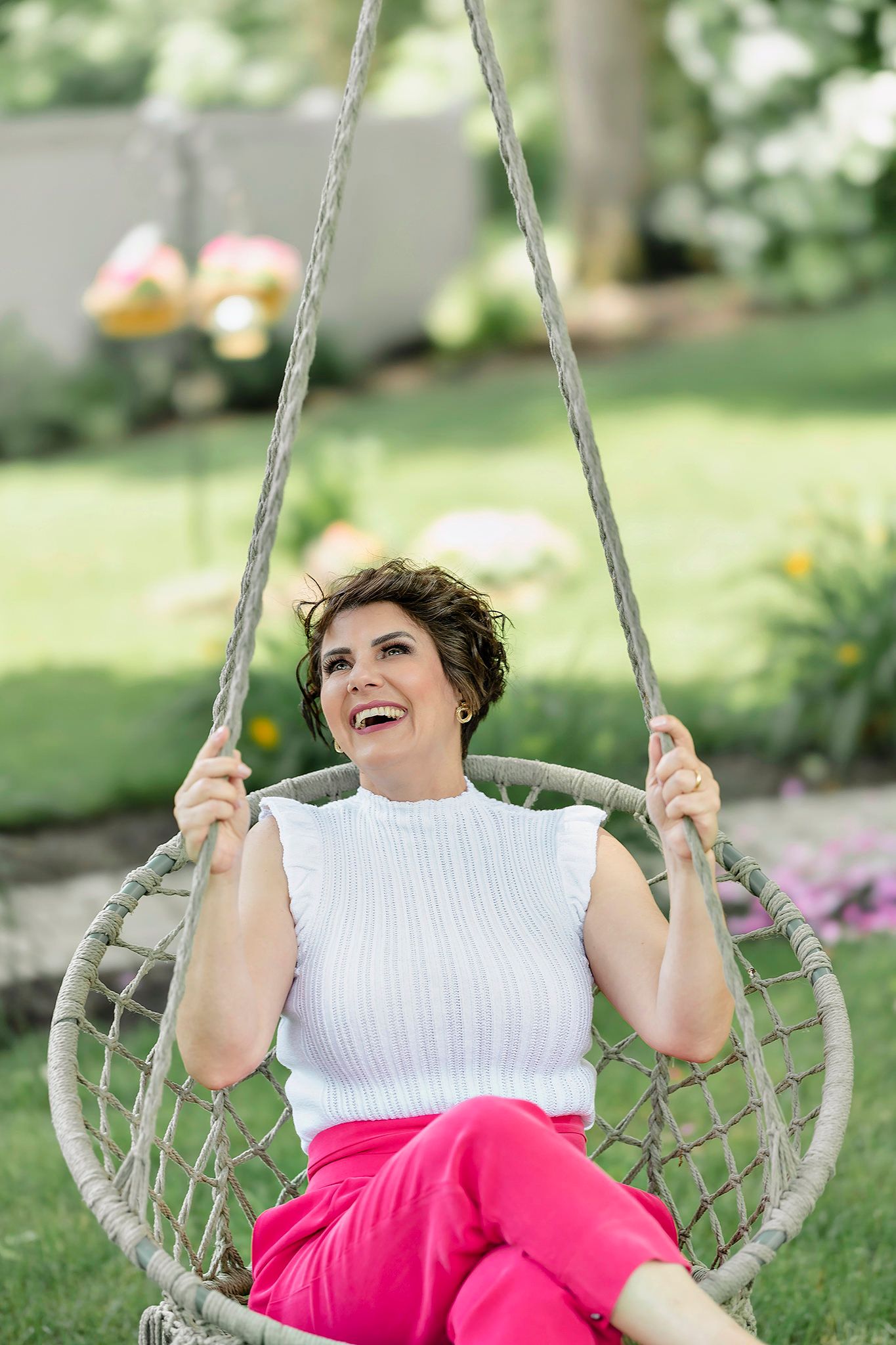 Person enjoying a relaxing moment on a hanging macrame swing chair in a garden setting.