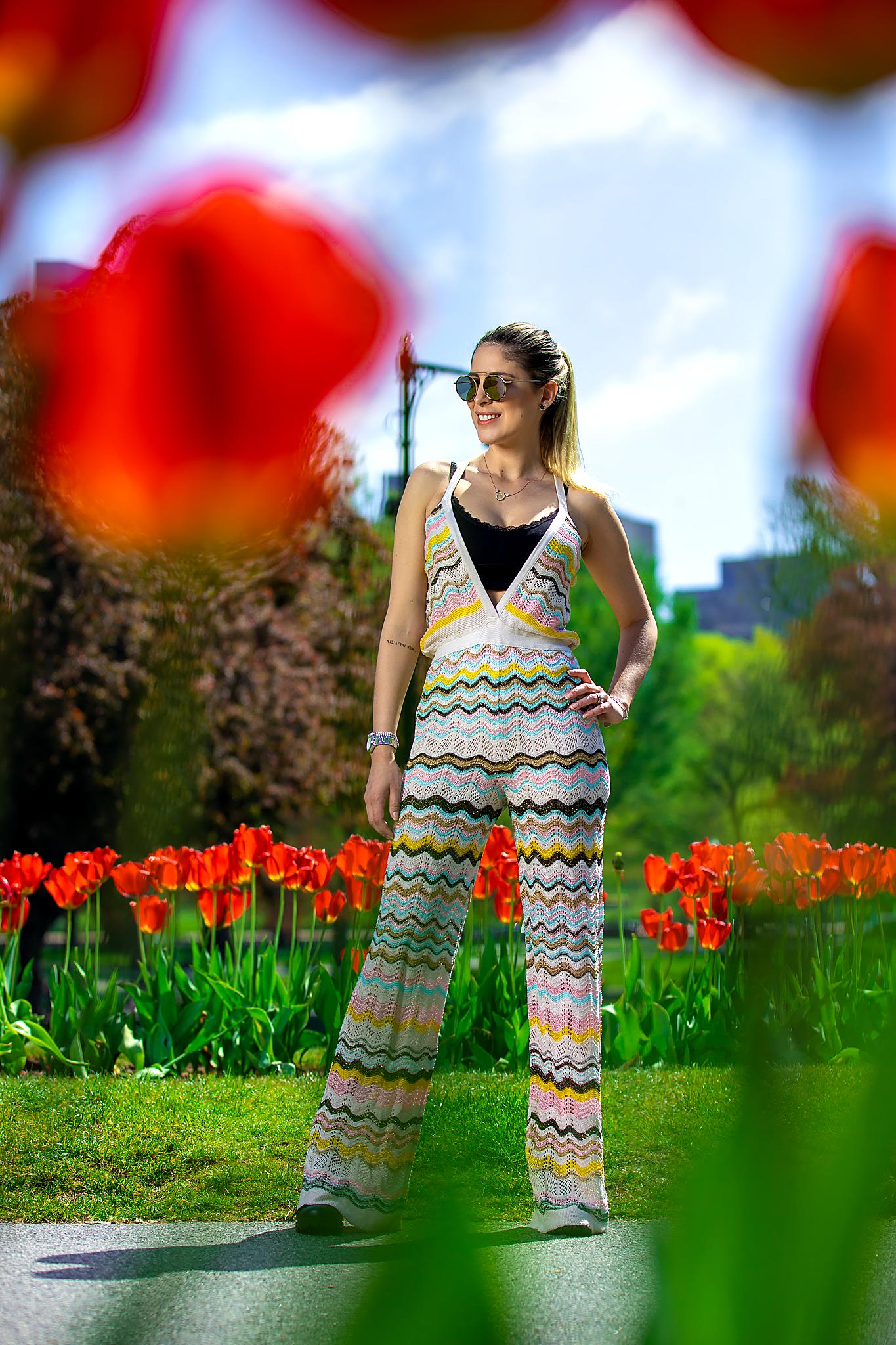 Chevron print dress captured through blooming red flowers in spring garden setting.