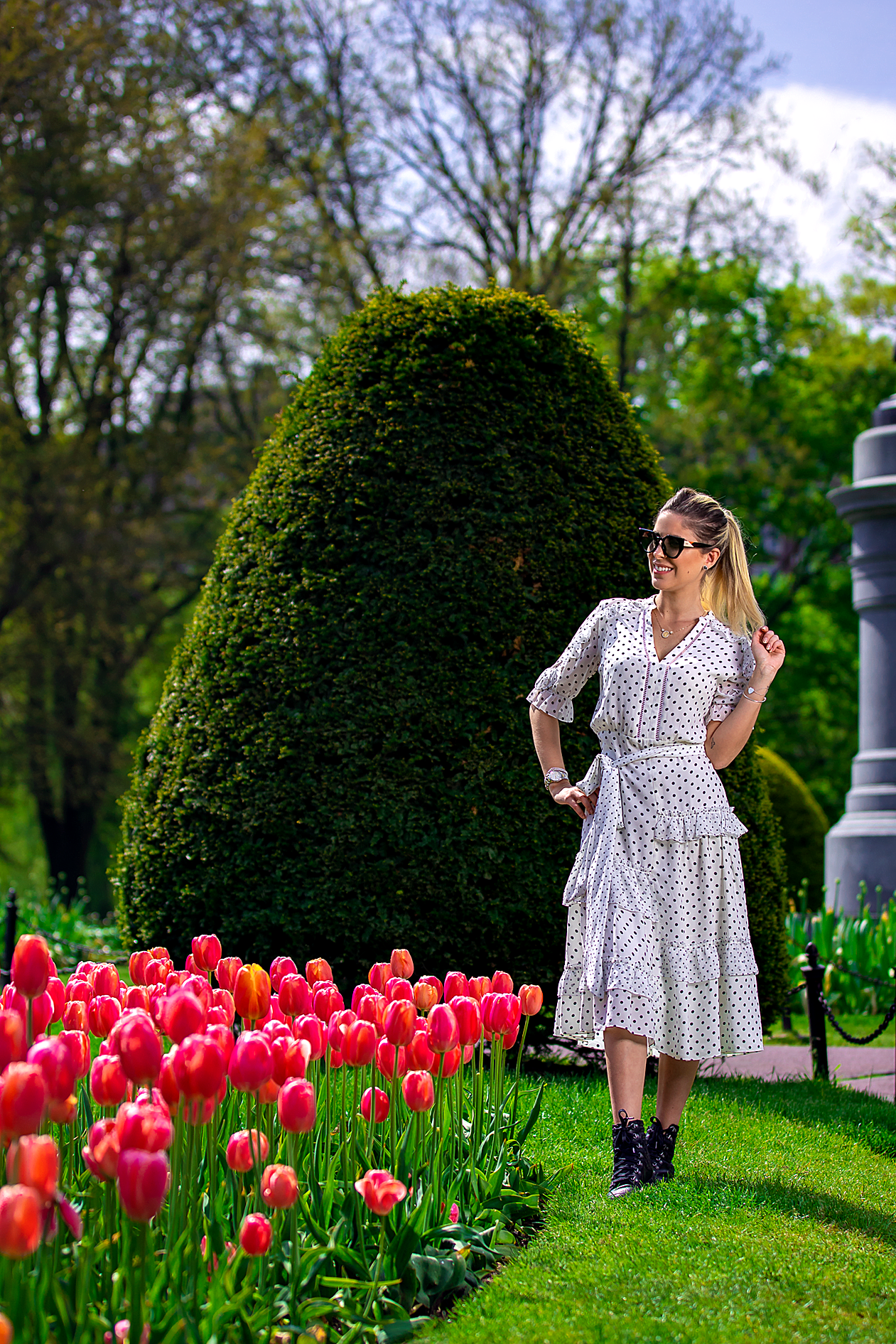 White dress photographed among vibrant red tulips and manicured garden landscaping.