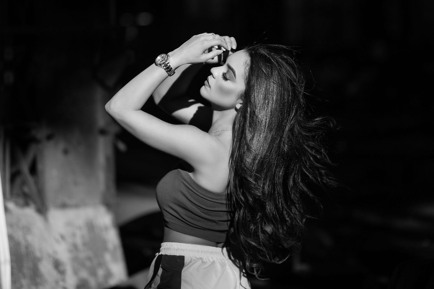 Black and white portrait of a woman with flowing dark hair posing dramatically against a dark background.