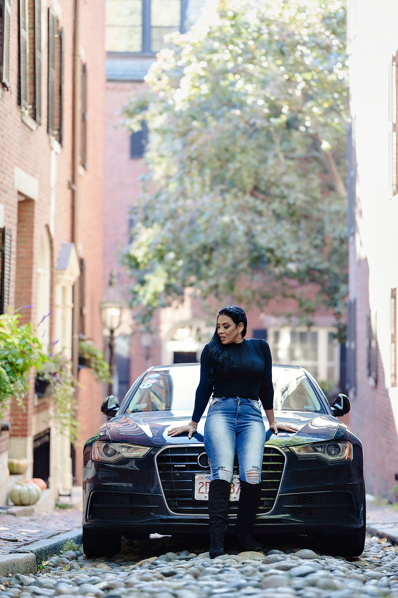 Dramatic urban photoshoot with vintage car on cobblestone street featuring dark styling.