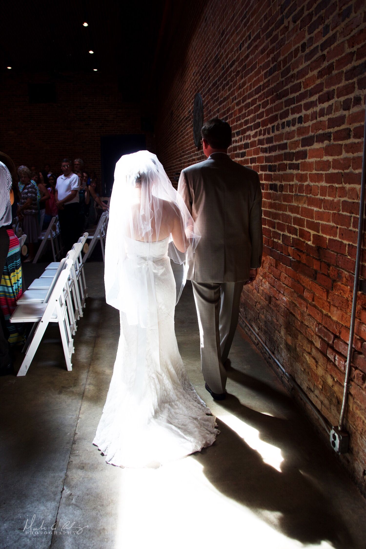A dramatic series of wedding photos showing a bride in white walking through a brick hallway with dramatic lighting.