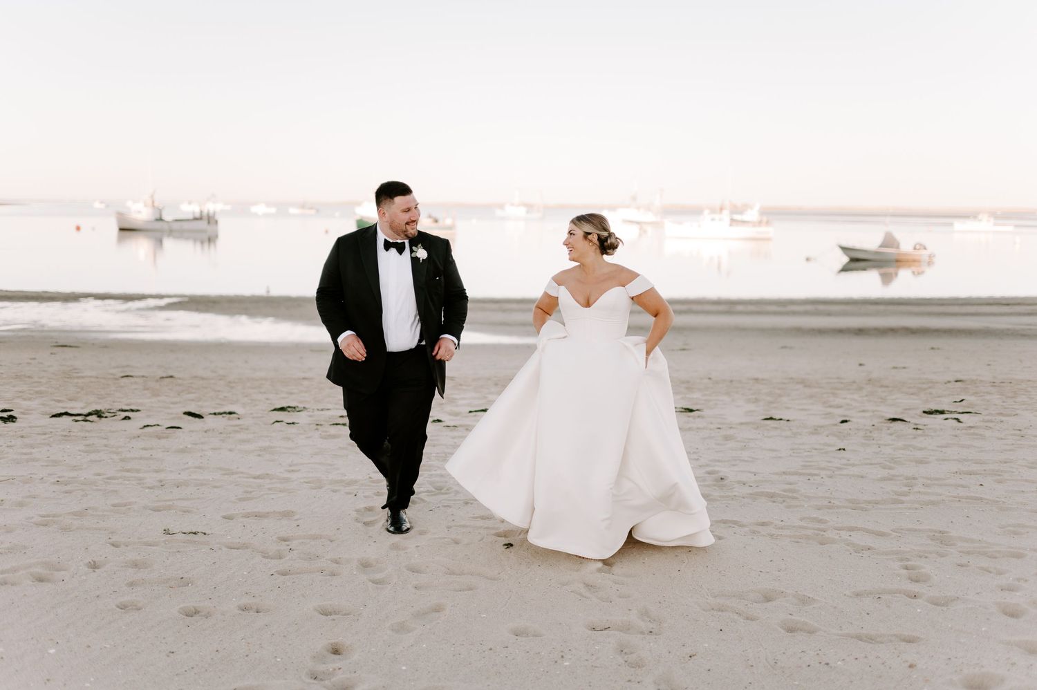 Wedding couple runs playfully along the shoreline during their beach photo session.