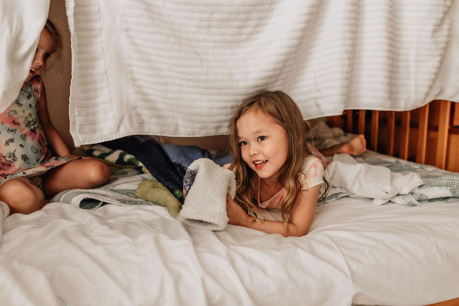 cousins building a fort on the bed at their vacation home in sandbridge beach, virginia
