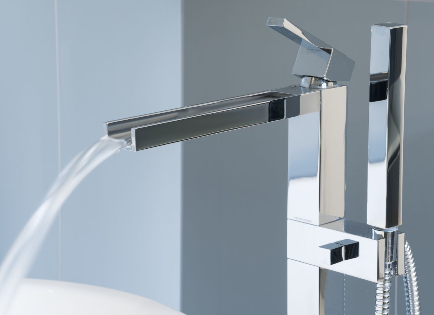 Modern chrome bathroom faucet with waterfall spout and square handle design showcasing running water.