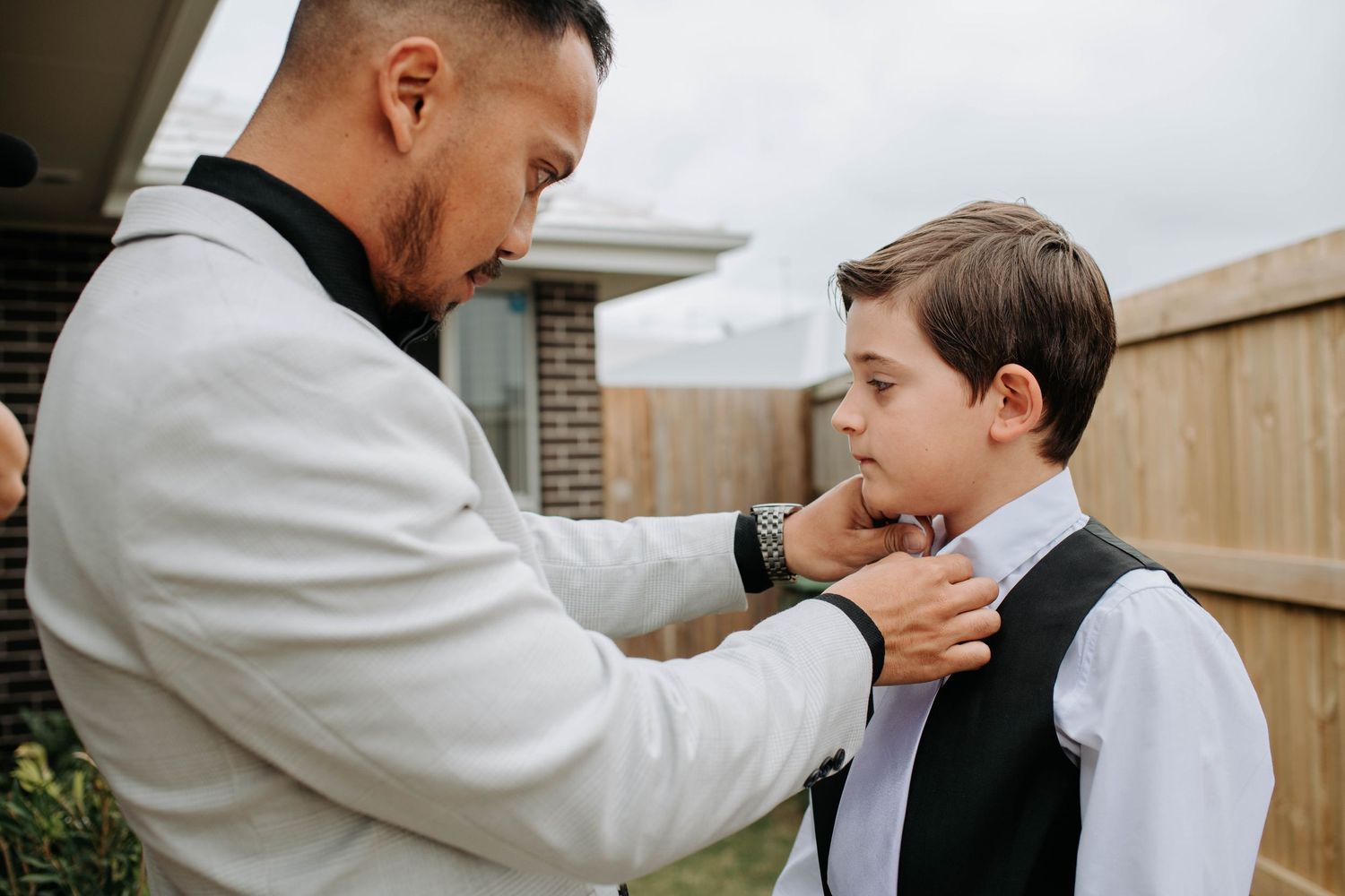 A touching moment of formal attire adjustment before a special event.