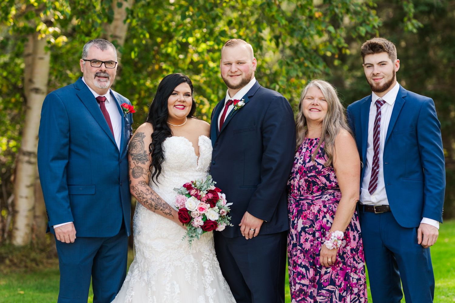 Wedding group photo with guests wearing coordinated navy blue and burgundy attire.