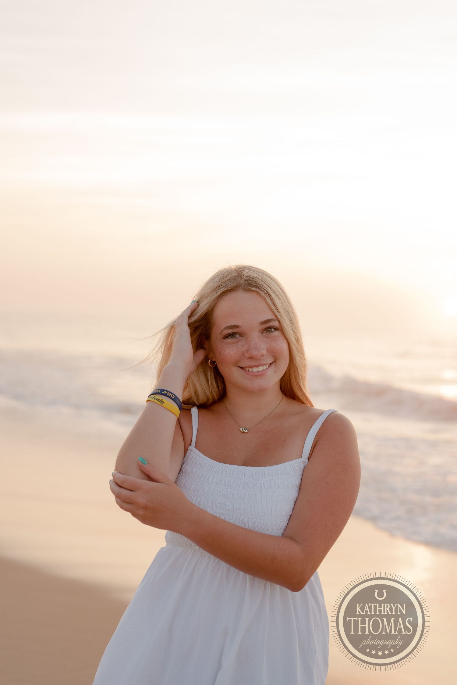Portrait of someone wearing a white sundress standing on a beach during golden hour.