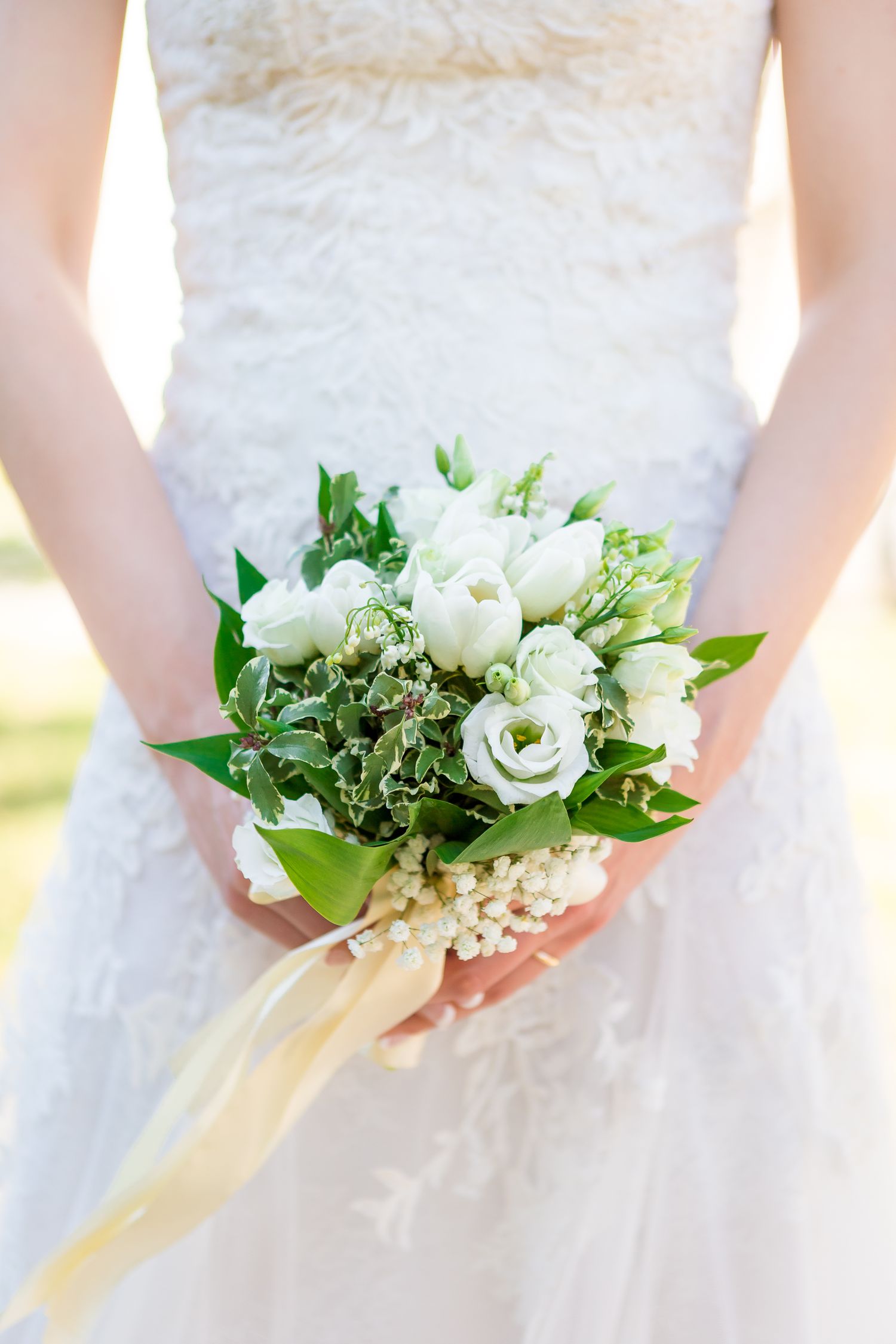 Sposa tiene in mano un bouquet nuziale con fiori bianchi