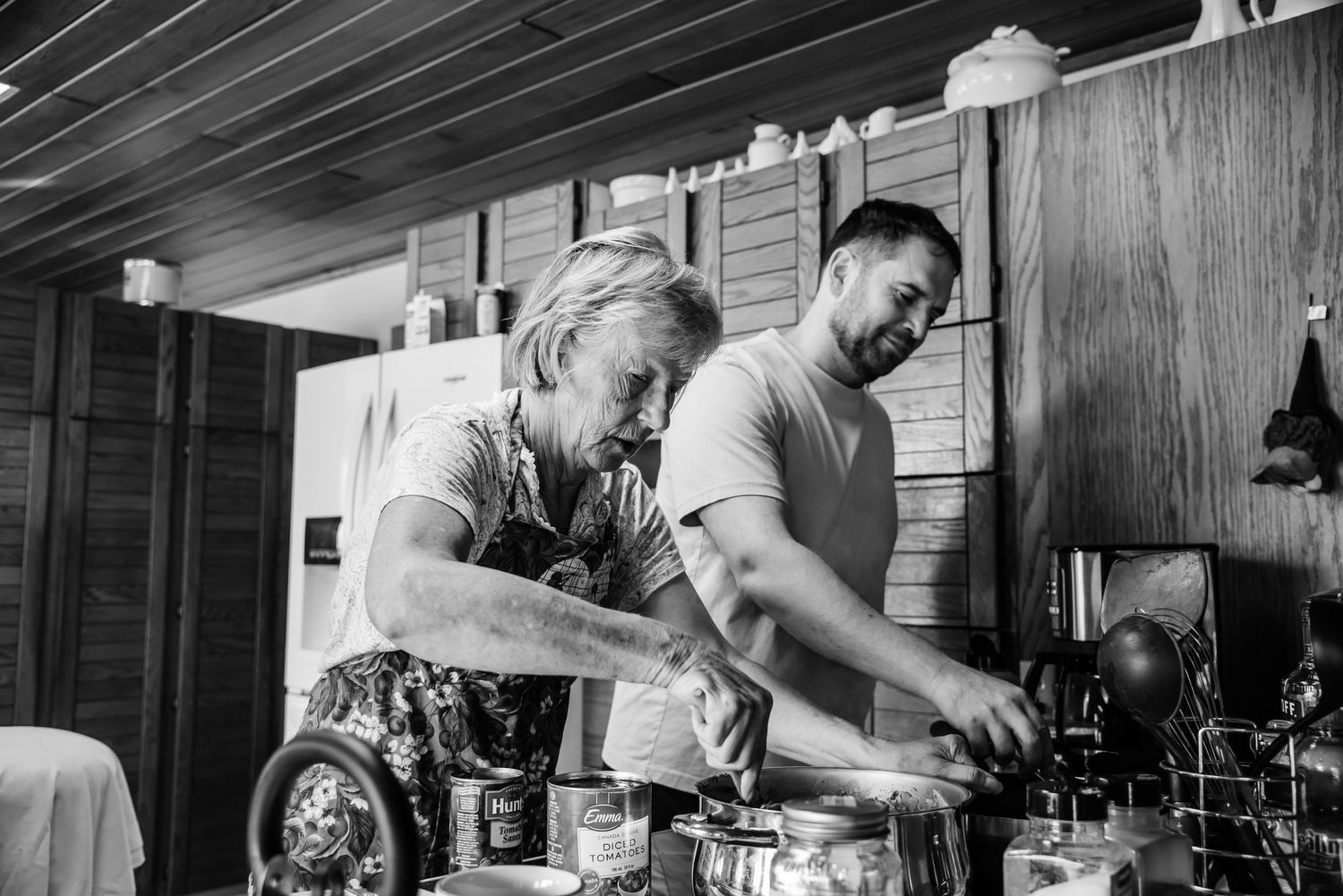 Two people cooking together in a rustic kitchen, preparing food side by side.