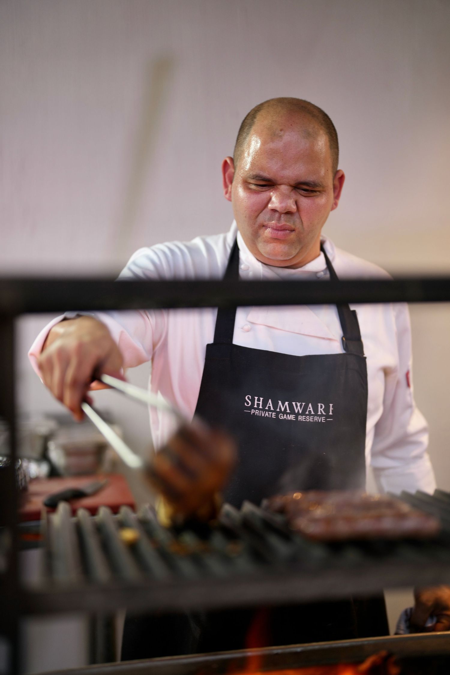 Chef in white uniform and black apron working in a restaurant kitchen.