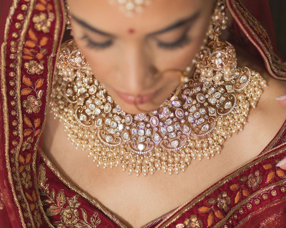 Close-up of ornate gold and diamond bridal necklace with red traditional Indian wedding attire.