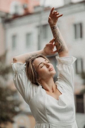 Expressive dance poses in a white flowing dress against an urban backdrop.
