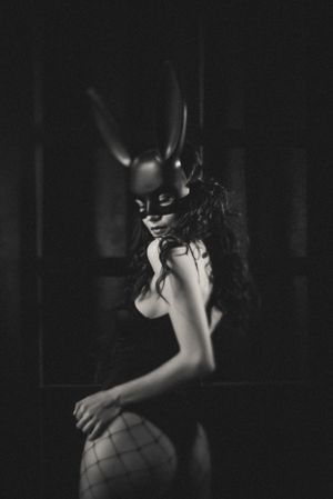 Dark artistic portrait featuring horned mask and dramatic shadows.