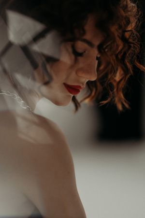 Close-up artistic portrait showing curly hair and red lipstick in soft focus.