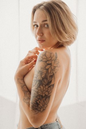 Artistic boudoir photo series showing a floral shoulder tattoo in natural window light.