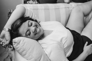 Person lying on white couch smiling and relaxing in black and white photo.