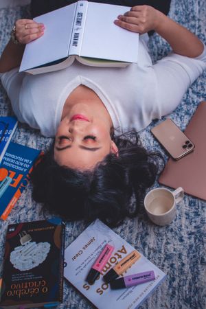 Overhead view of student materials including books, markers, and coffee cups scattered on a blue textured carpet.