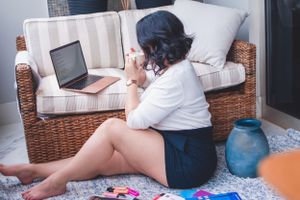 Person relaxing on a striped couch surrounded by study materials and a laptop.