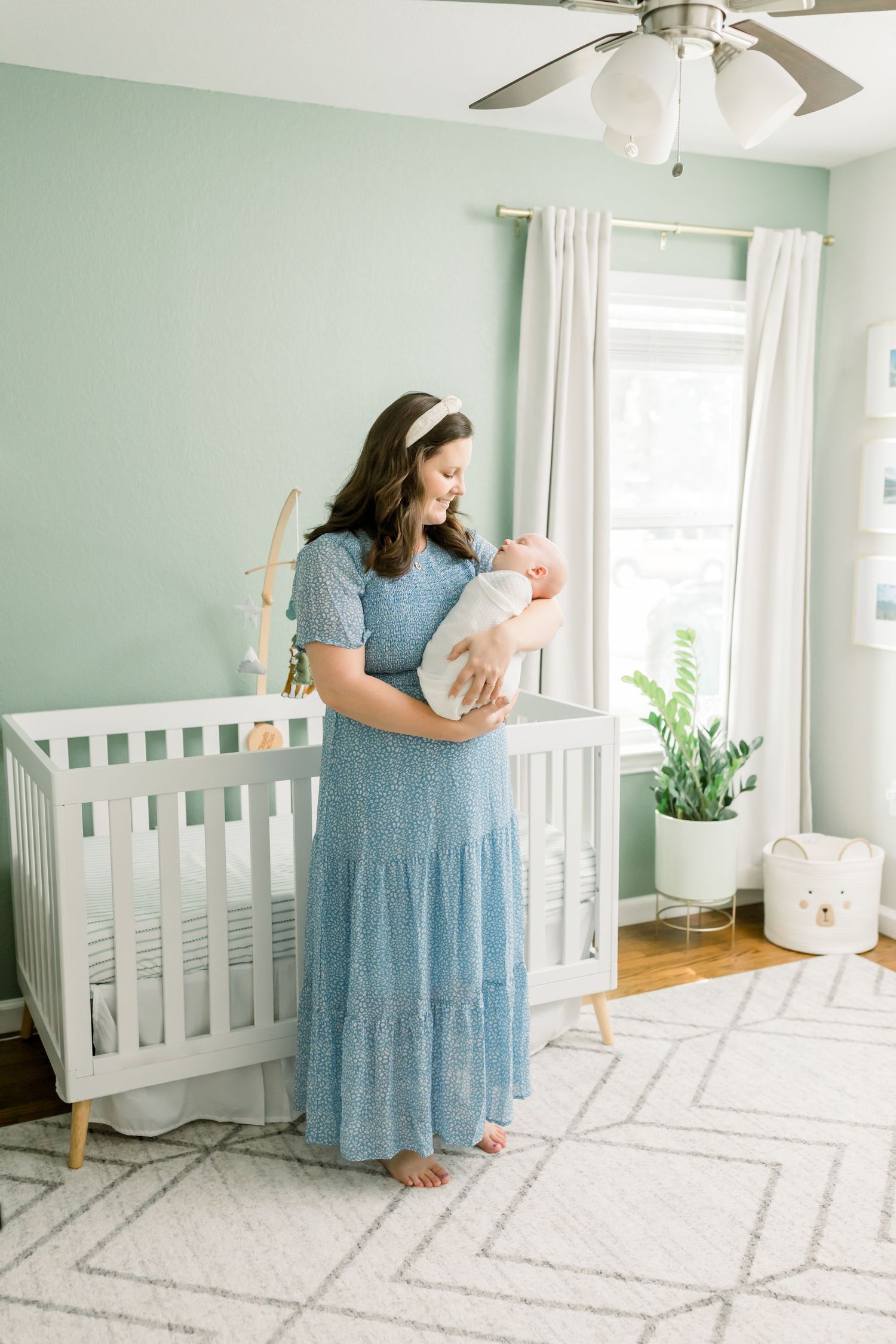 A peaceful nursery scene with mint green walls, white crib, and geometric rug.