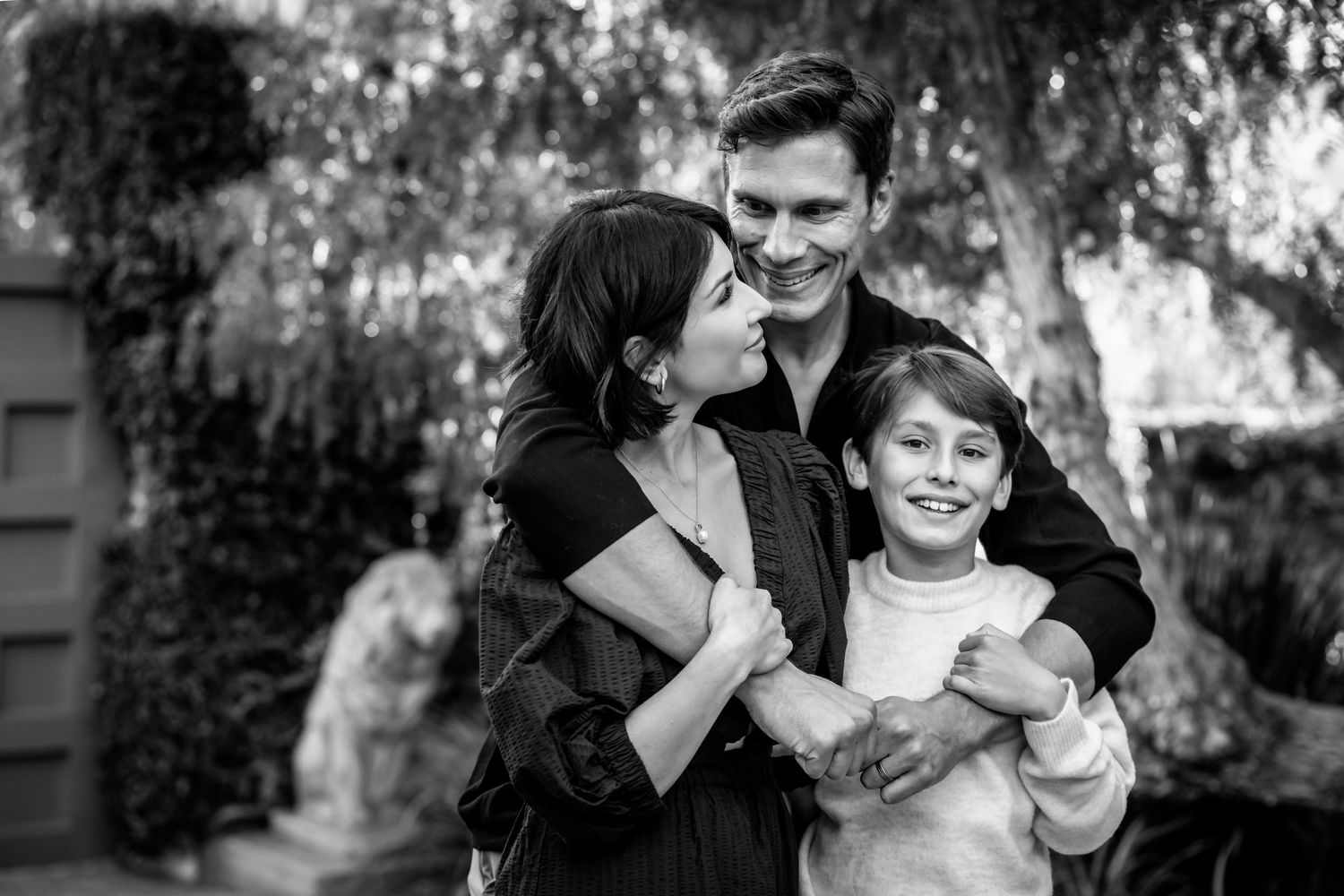 A joyful family moment captured in black and white under a willow tree.