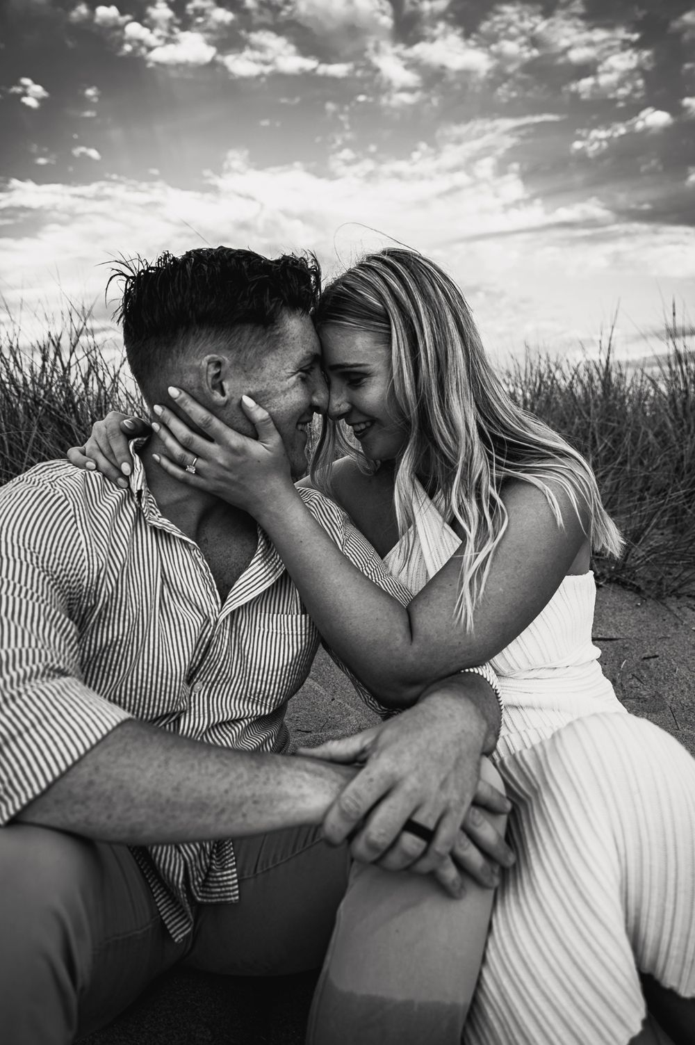 Black and white series shows intimate moments between couple in tall grass field.