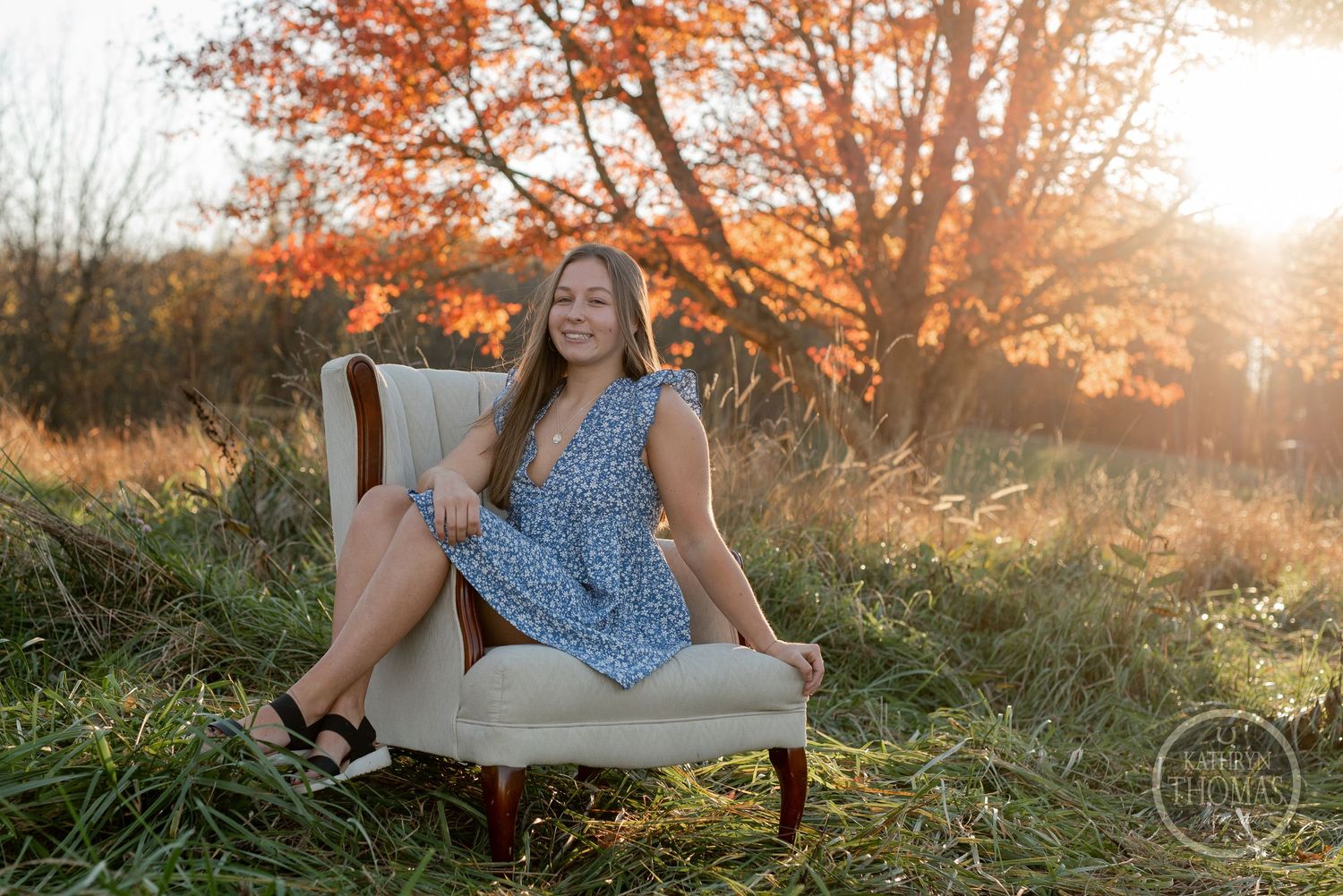 A blue summer dress against a beige armchair in a field during golden hour.