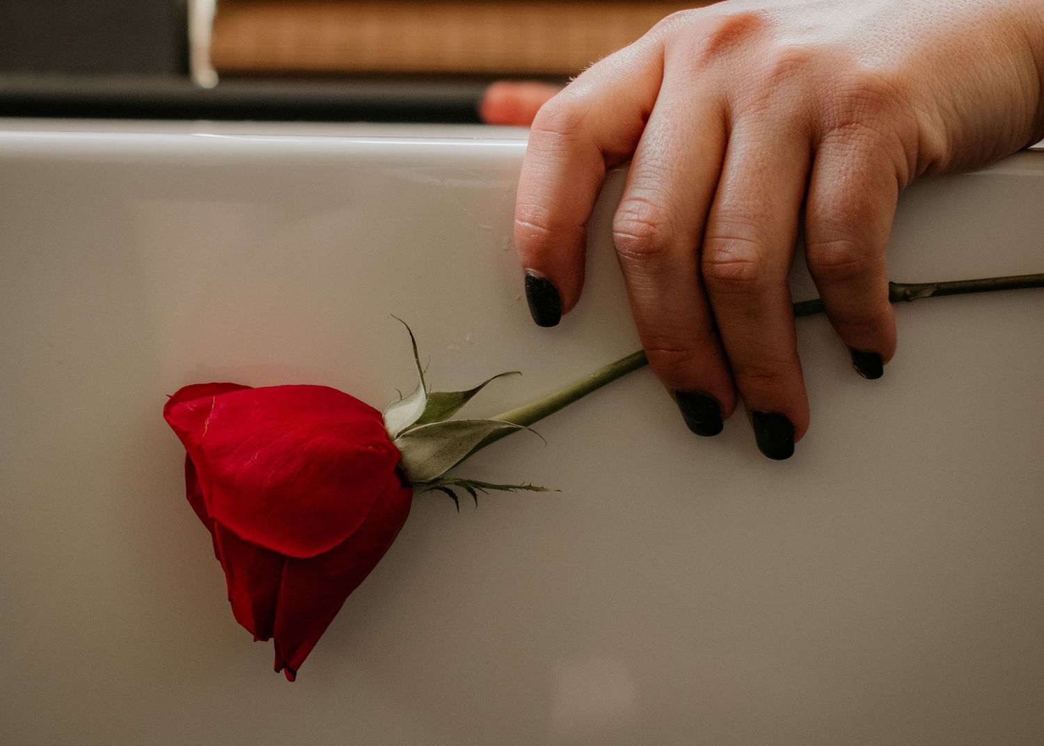 lady holding a rose on the edge of a bathtub during boudoir session