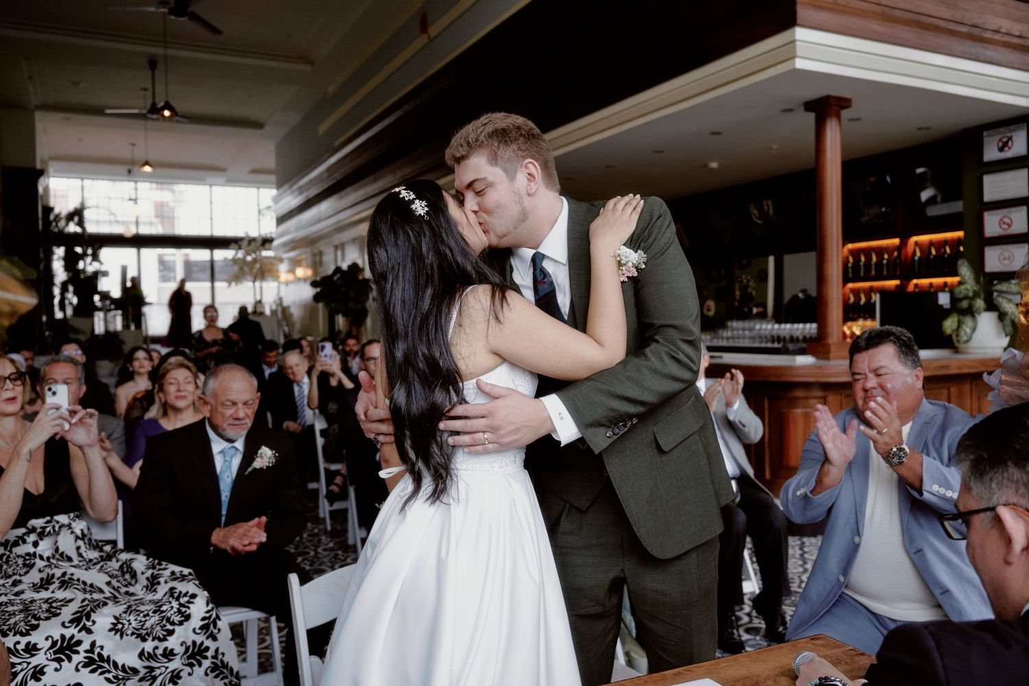 A newlywed couple shares their first dance surrounded by applauding guests.