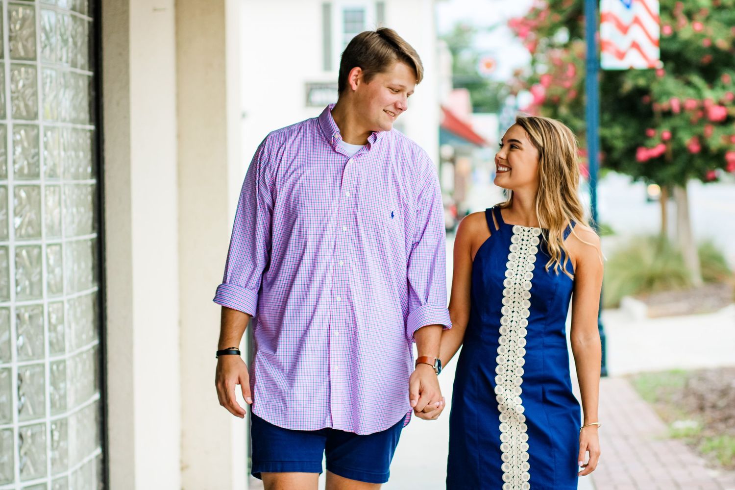 Couple walking together on sidewalk wearing coordinated blue and purple outfits.