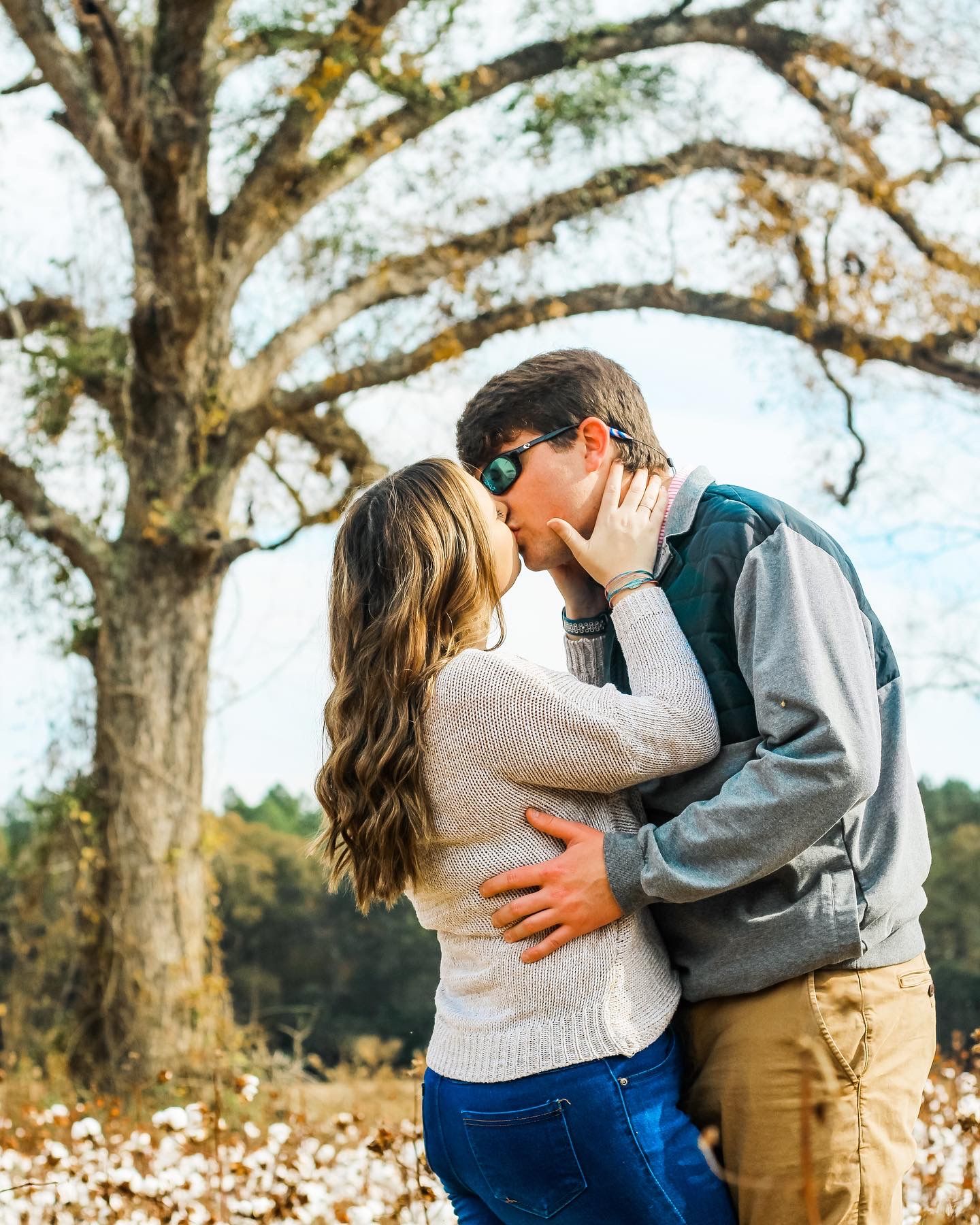 Romantic autumn couple sharing intimate moment under large oak tree.