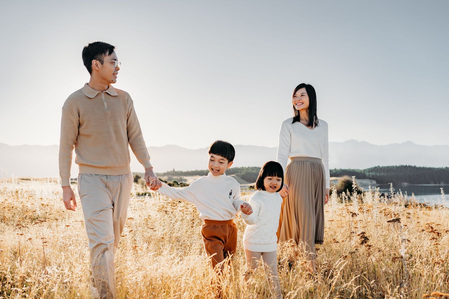 A family takes a stroll together through a sun-drenched autumn field.