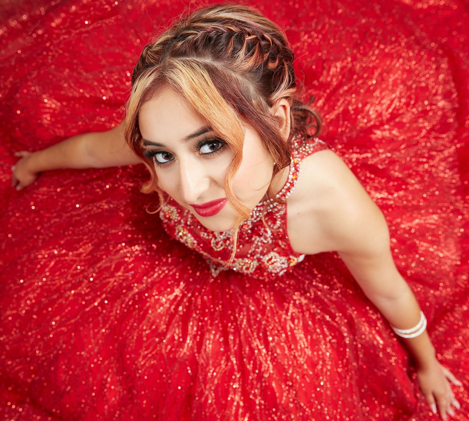 A dramatic overhead view of someone in a sparkling red ballgown with intricate beading.