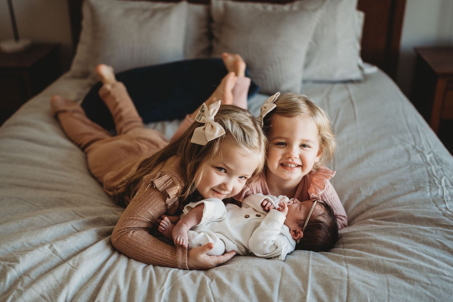 A sweet family moment captured in bed as they cuddle and play together on white linens.