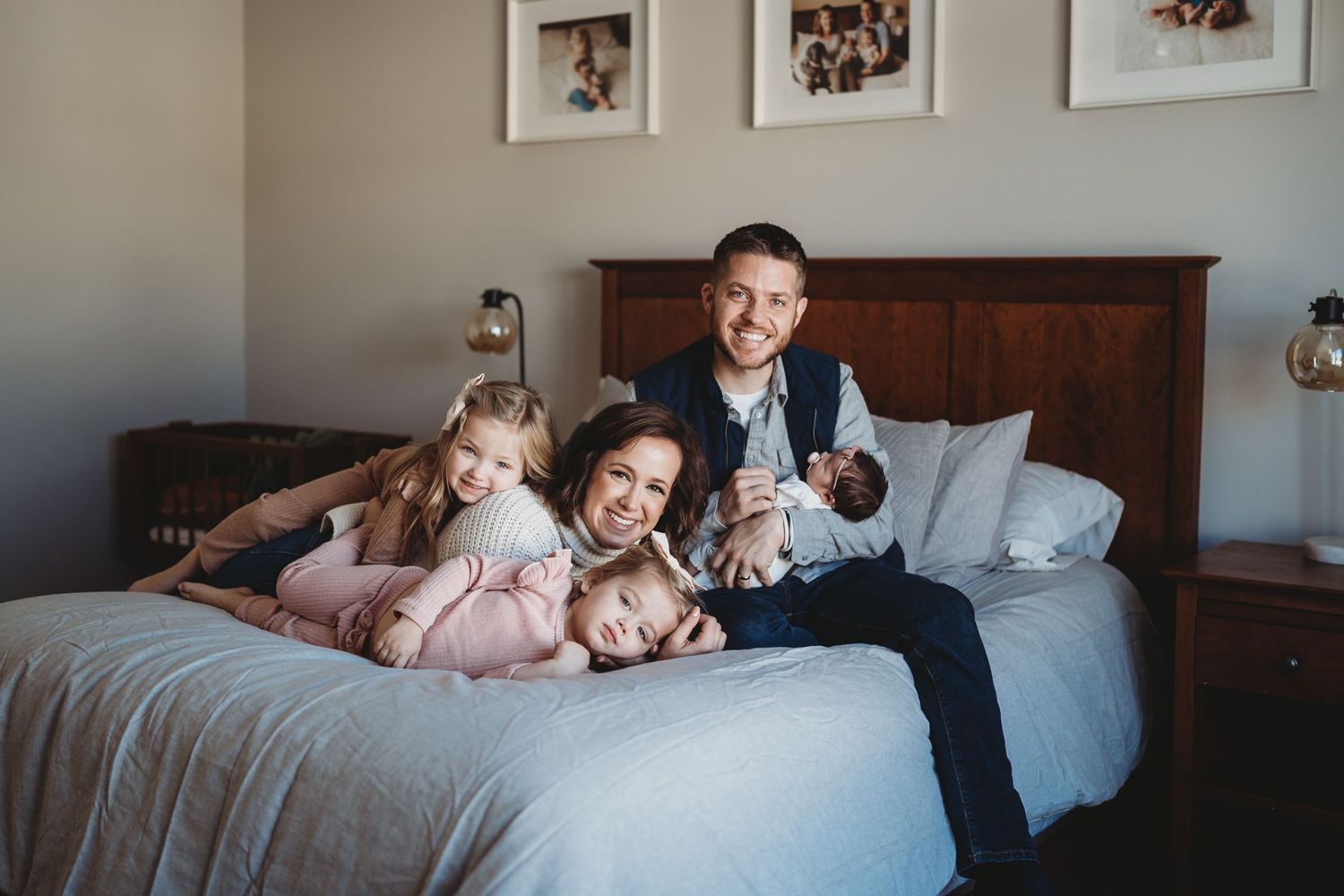 Family snuggling together on a large bed during an intimate photoshoot.