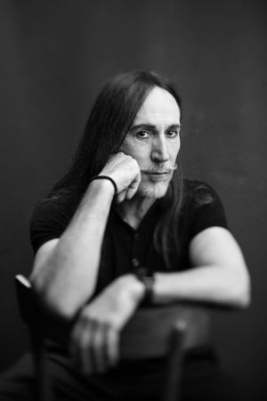 Dramatic black and white portrait with long dark hair against dark background.