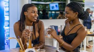 Two friends sharing drinks and conversation at a modern indoor cafe setting.