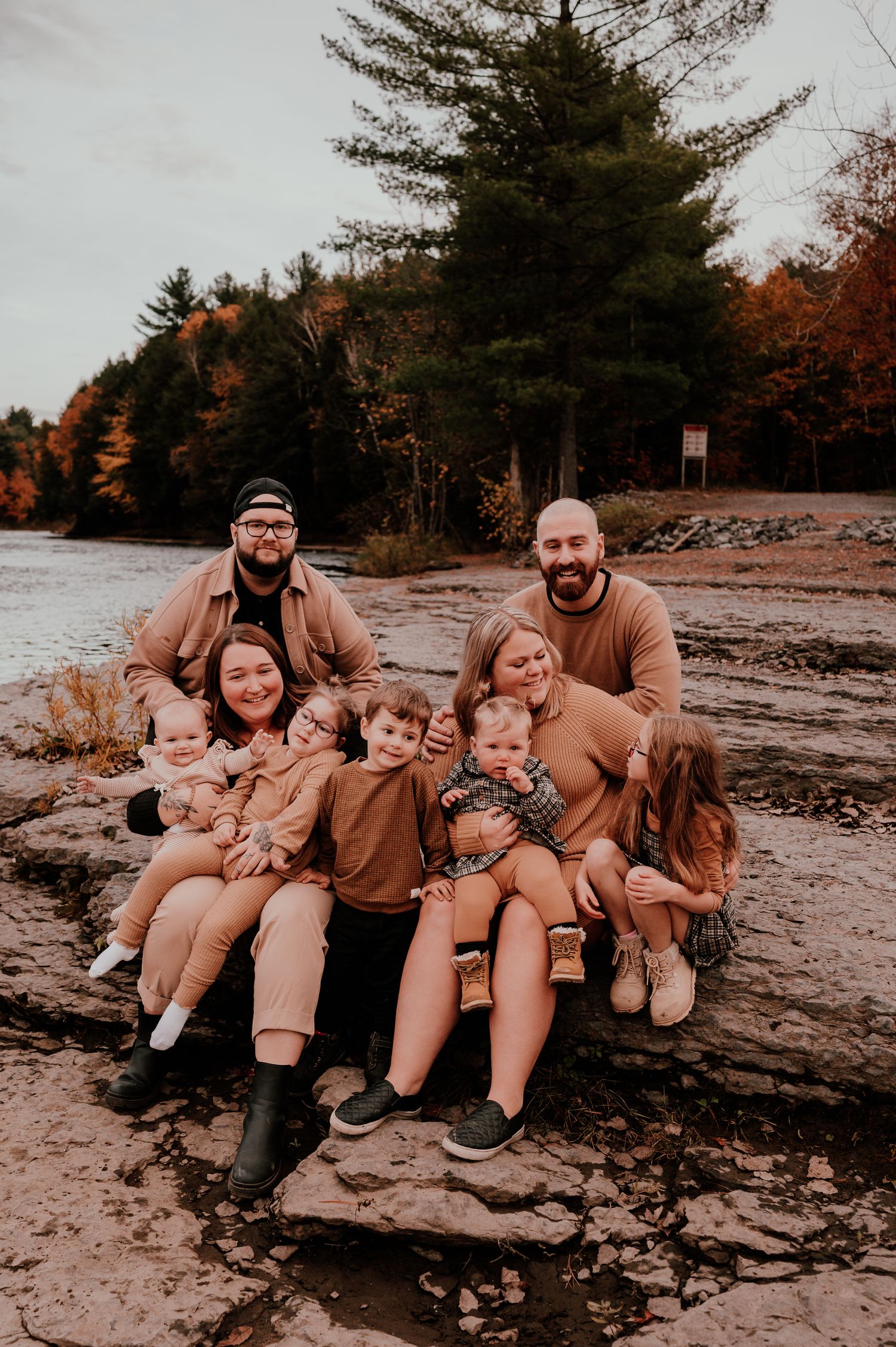 Family group sitting together on rocky beach during autumn.