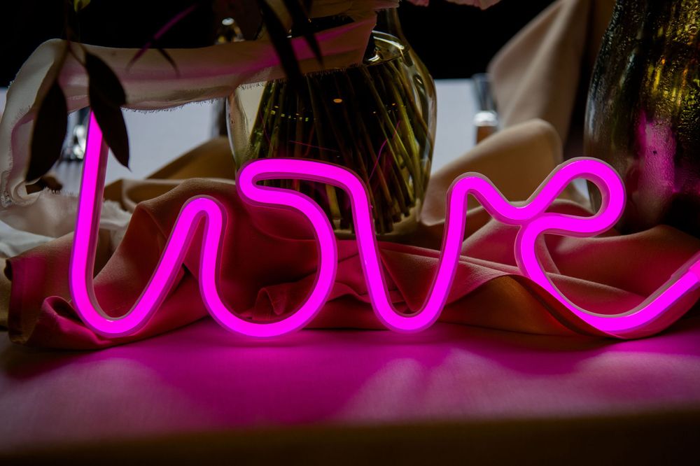 A pink neon sign spelling out 'love' glows against a dark background.