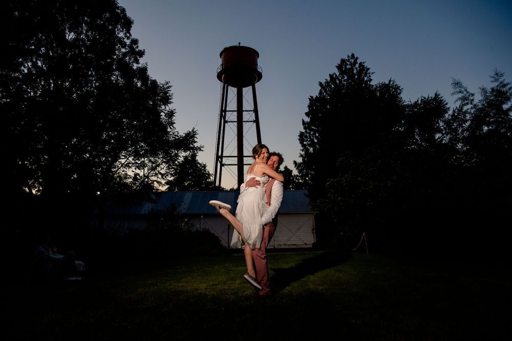 A romantic silhouette of a couple embracing near a water tower at dusk.