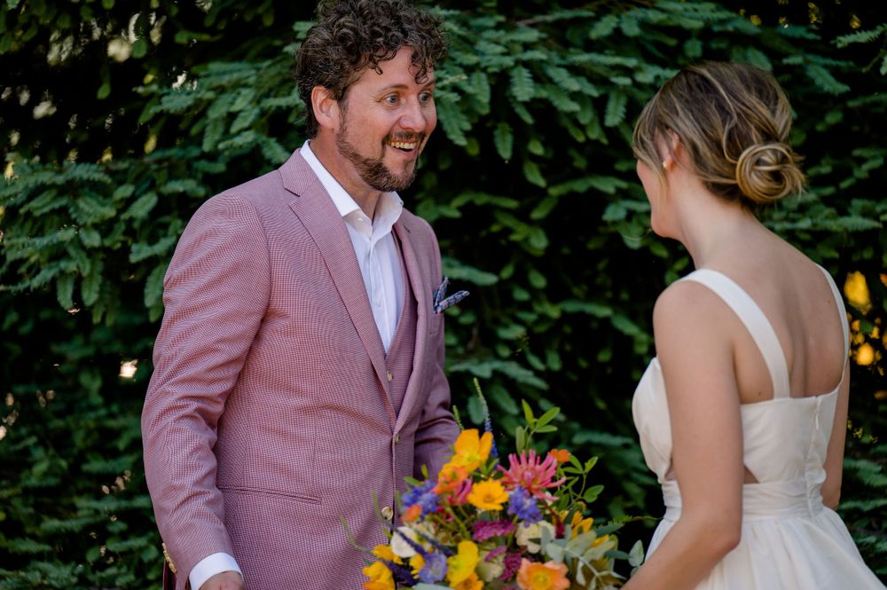 A couple shares a joyful moment in a garden with vibrant flowers and greenery.