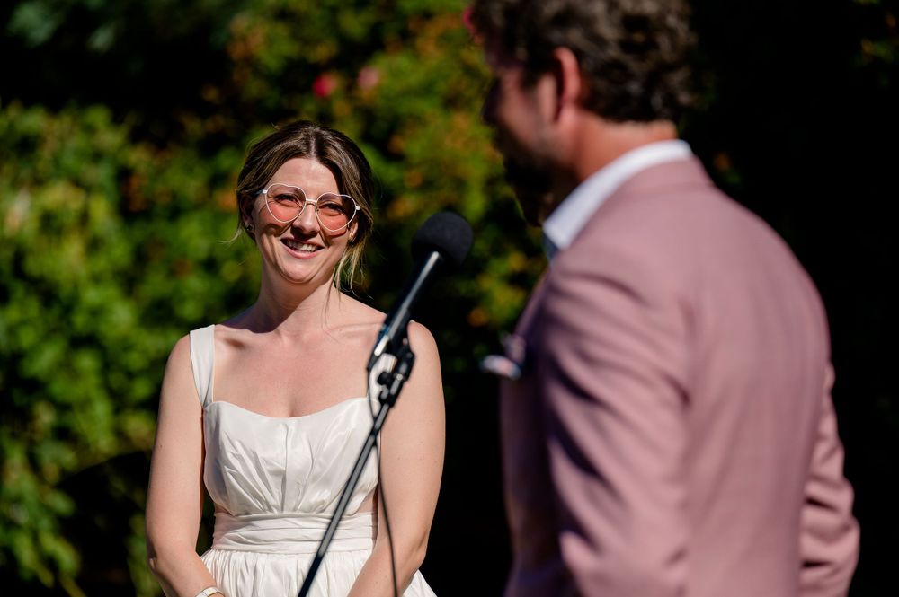 A candid moment during wedding vows at an outdoor garden ceremony.