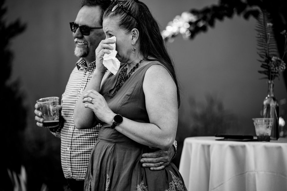 Emotional black and white candid moment during outdoor wedding reception.
